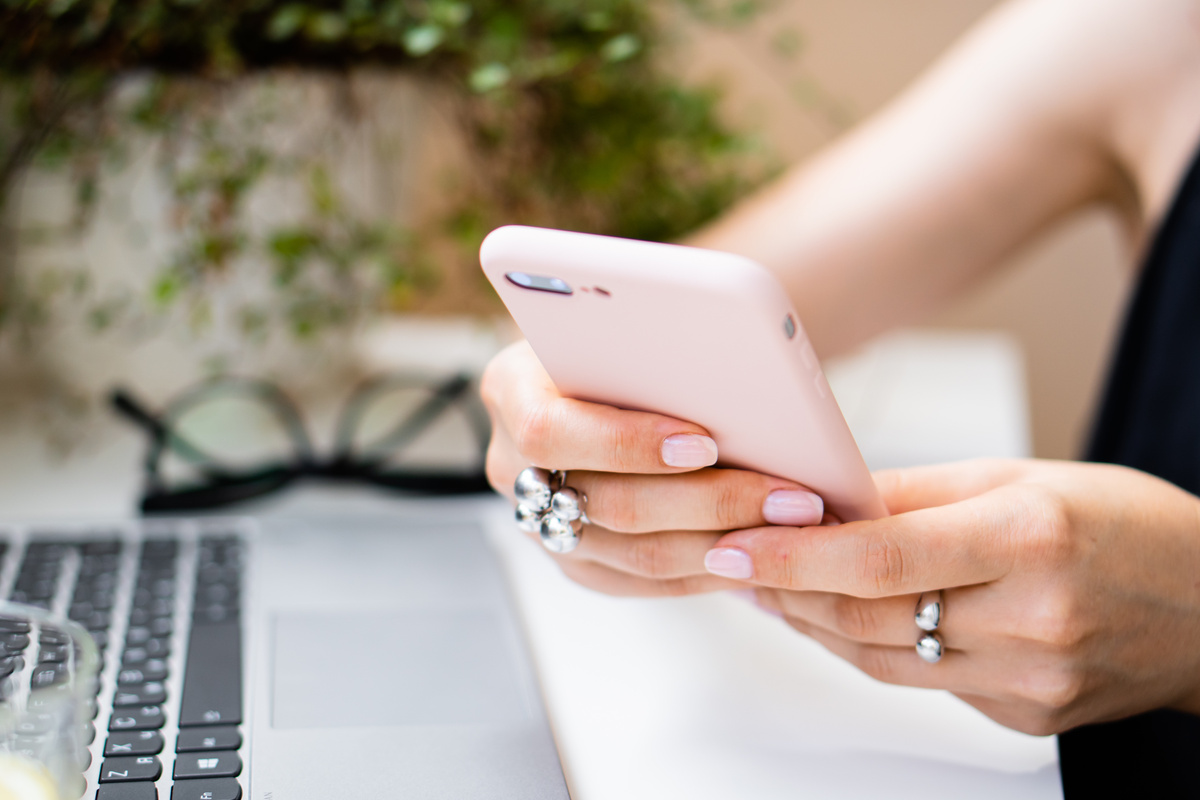 Woman's Hand Holding a Smartphone in a Cozy Office Workspace